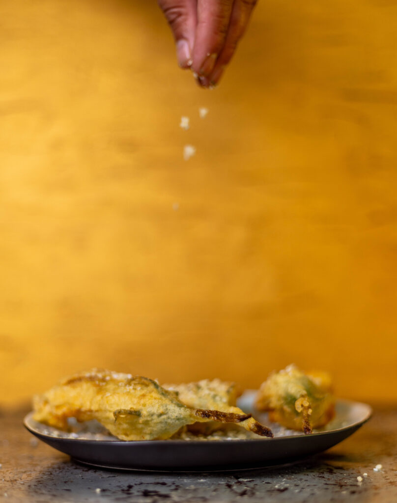 7. Zum Schluss wird noch etwas Macadamia Parmesan auf die frittierten Zucchiniblüten gestreut.