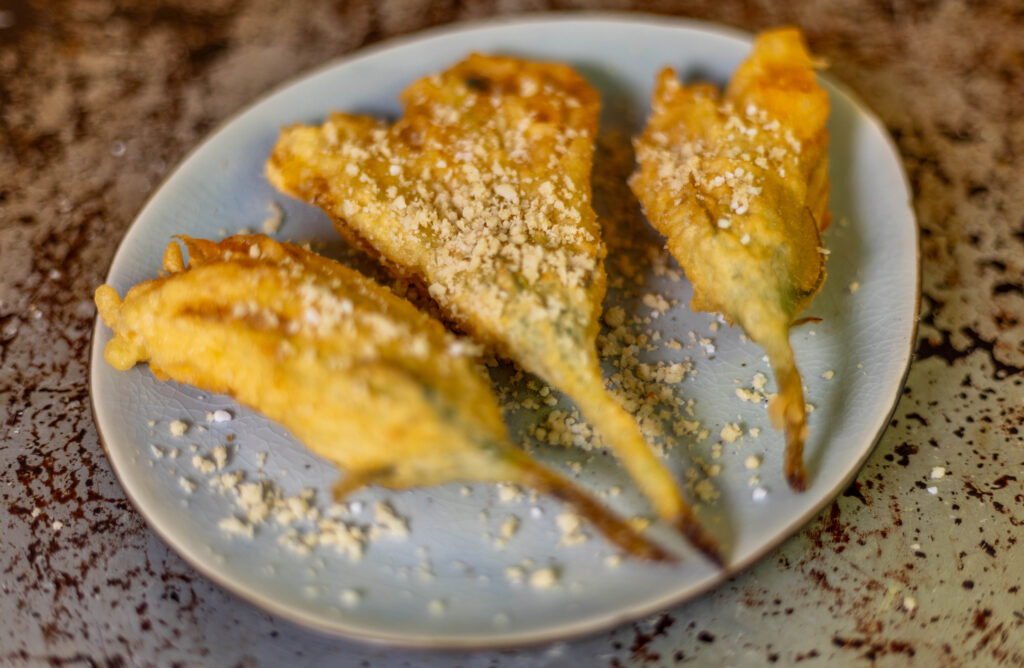 Selbstgemachter Macadamia Parmesan schmeckt köstlich auf frittierten Zucchiniblüten.