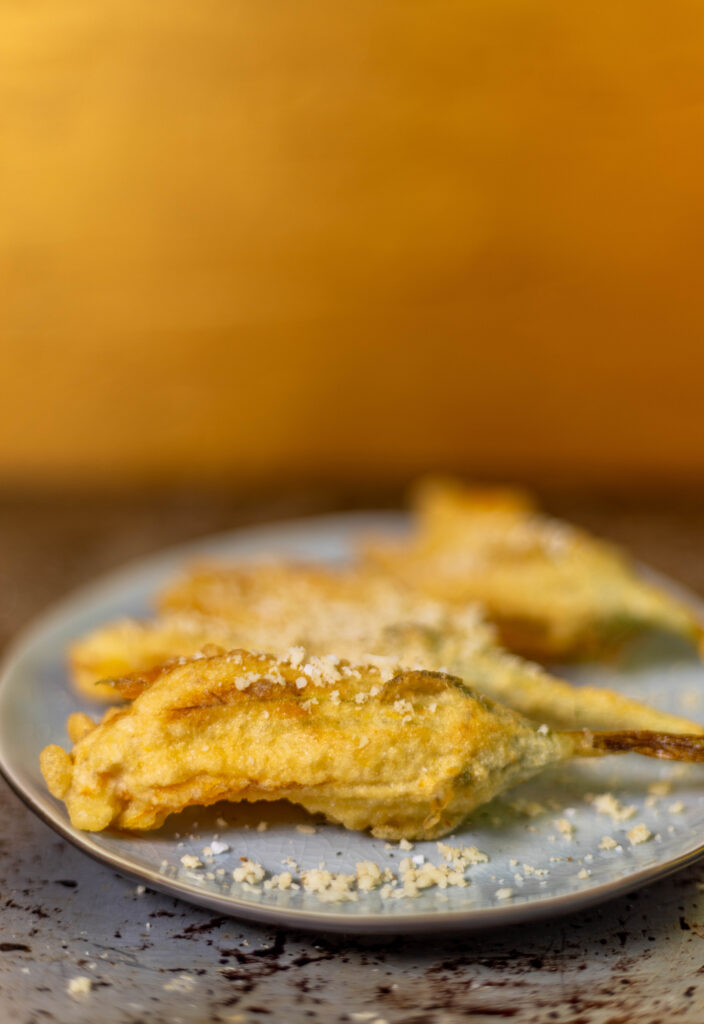 Ich habe die frischen, goldenen Zucchiniblüten in einem knusprigen Tempura-Teigmantel frittiert.