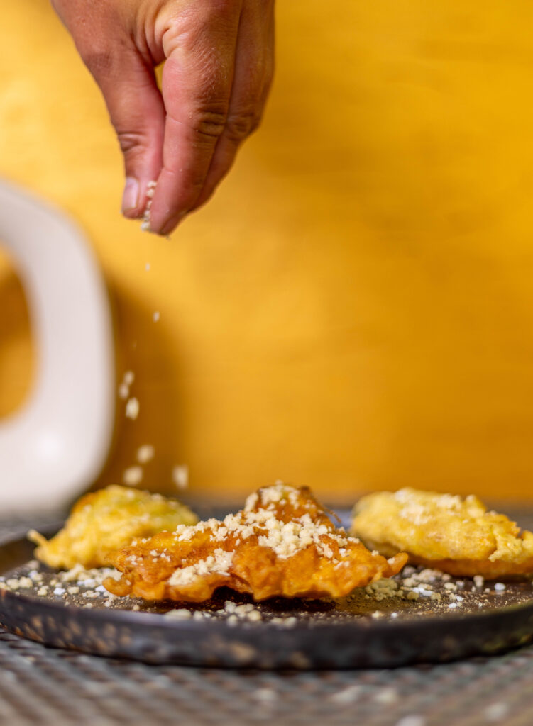 Macadamia Parmesan wird über frittierte Zucchiniblüten gestreut.