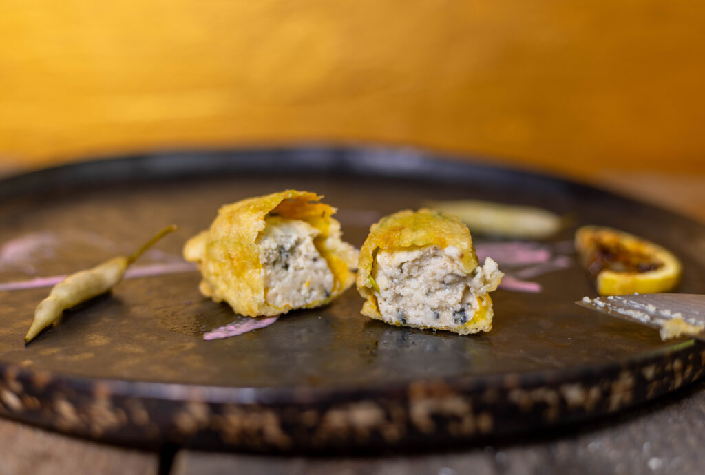 Gefüllte Zucchiniblüten mit einer cremigen, aromatischen Füllung in Teig ausgebacken.