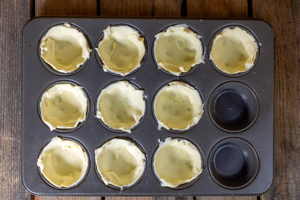 2. Auskleiden der Förmchen im Muffinblech mit dem Blätterteig.