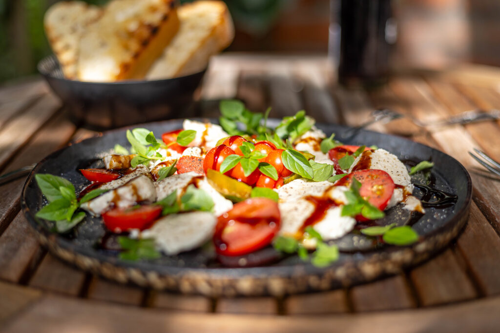 Veganer Mozzarella Caprese im Garten mit selbstgezogenen Tomaten und selbstgemachtem Mozzarella