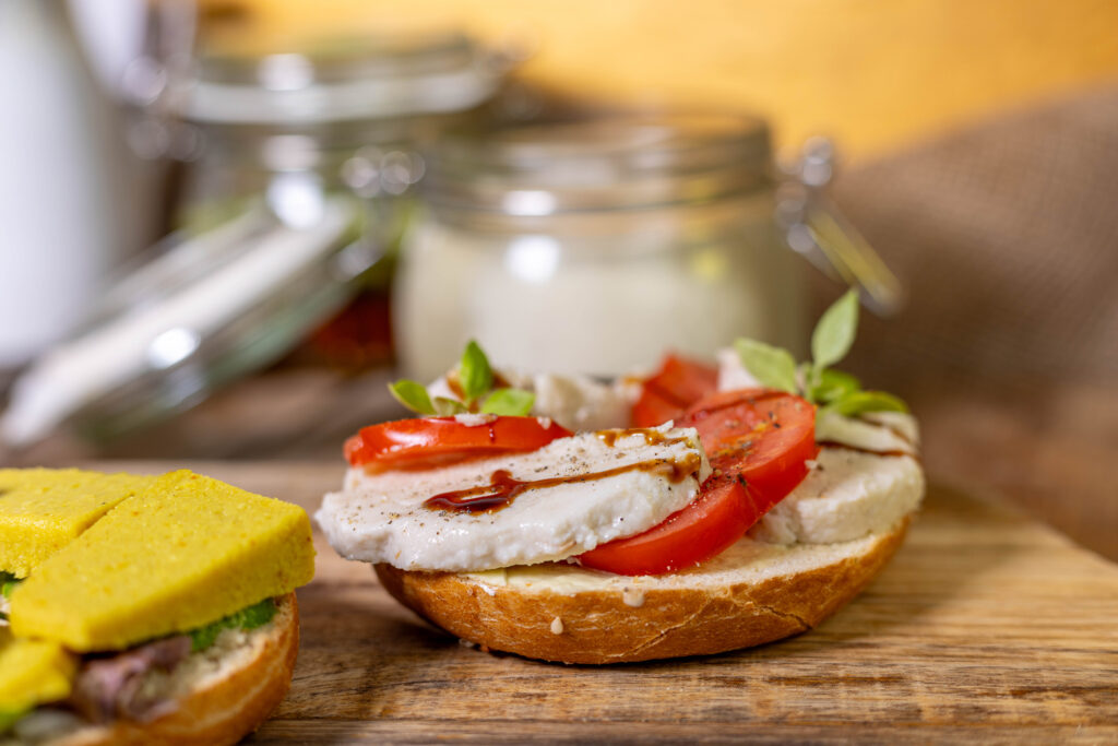 Selbstgemachter veganer Mozzarella auf einem Bagel mit Tomate.