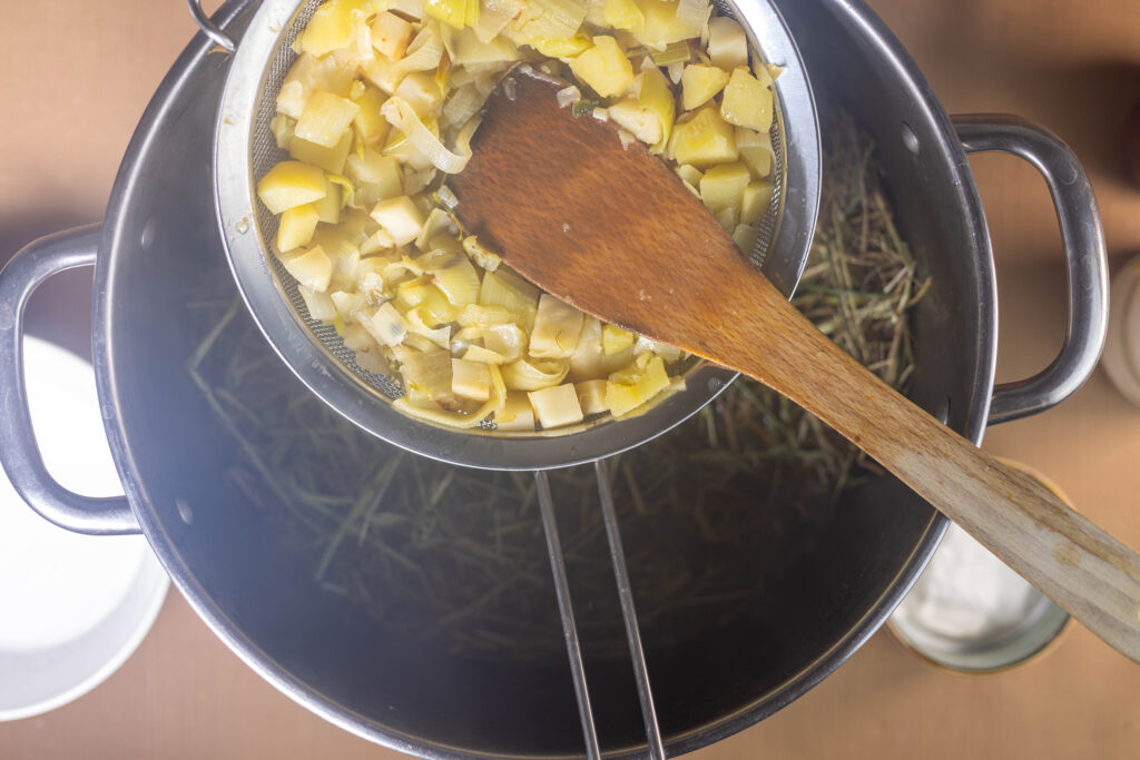 6. Das Gemüse aus der Heusuppe absieben und dann das Heu in die heiße Suppe geben.