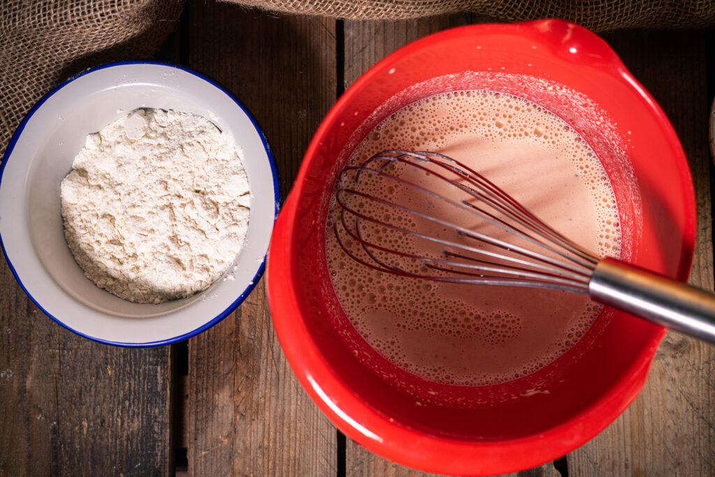 2. In einer großen Schüssel das angerührte Kichererbsenmehl mit der Sojamilch, der veganen Creme Fraiche sowie den Gewürzen verrühren.