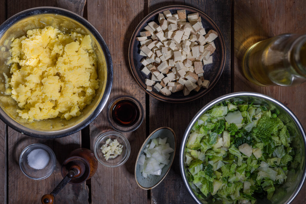 2. Die Kartoffeln stampfen, Gemüse zerkleinern und Räuchertofu würfeln.