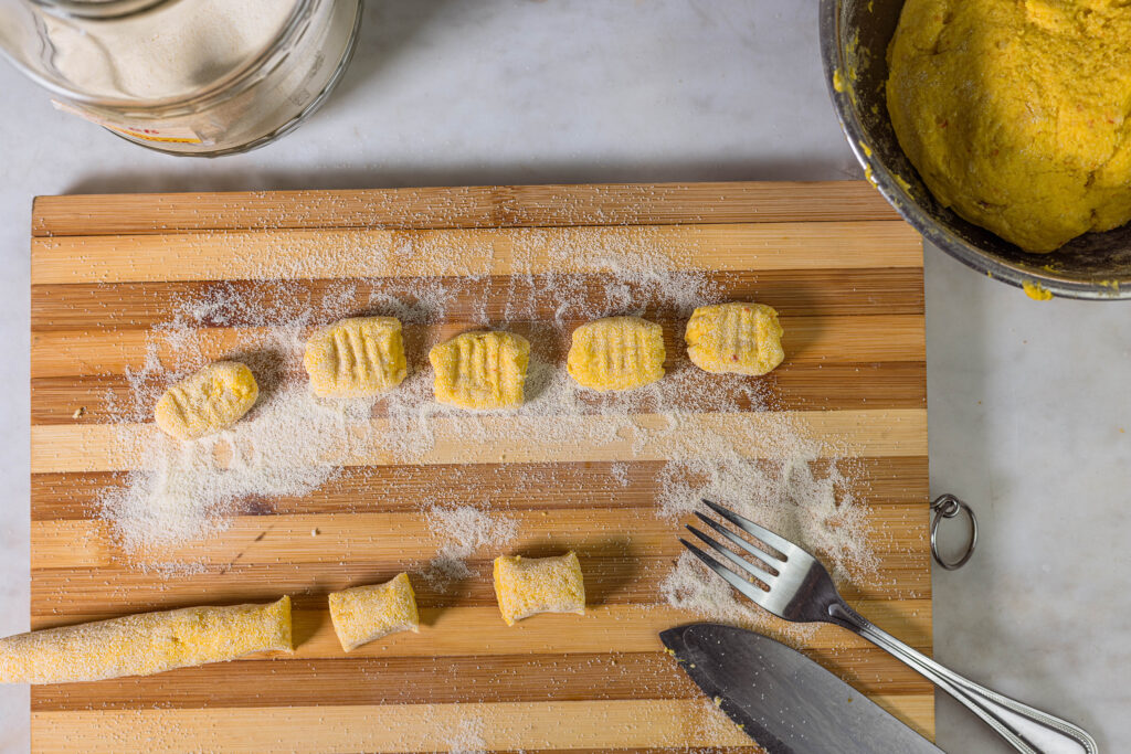 4. Den Gnocchi-Teig auf Grieß zu langen Würsten ausrollen. Diese in Abschnitte teilen und mit der Gabel leicht eindrücken.