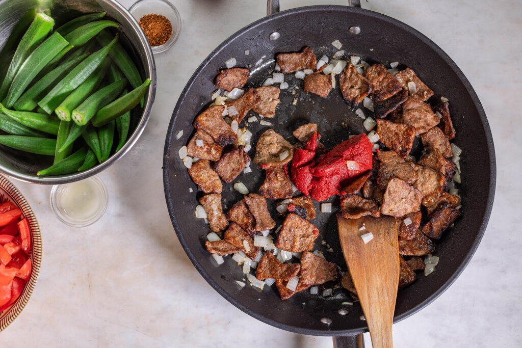 5. Das Vleisch wird mit Tomatenmark und Harissa weiter gebraten.