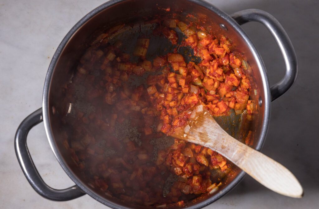 4. Als nächstes die Karotte, Selleriestange und das Tomatenmark einrühren. Erneut kurz anbraten.