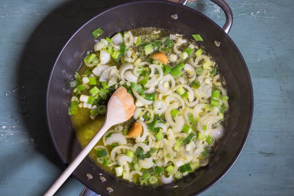 3. Zwiebeln, fermentierter Knoblauch und Lauchzwiebeln werden in veganer Butter und Olivenöl geschmort.