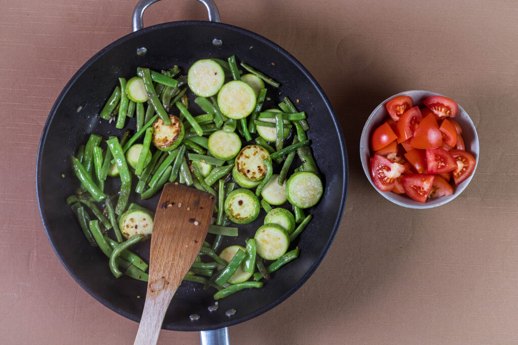 7. Öl in einer Pfanne erhitzen und die grünen Bohnen, Zucchini, Knoblauch und Chiliflocken hinein geben.