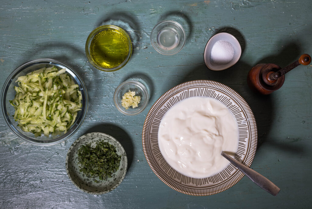 2. Die Gurke ist gerieben, die Minze gehackt und der Knoblauch gepresst. Die Gurkenstücke wurden ein wenig mit den Händen ausgedrückt, um Flüssigkeit zu verlieren.