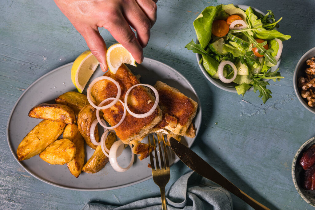 Saganaki mit Salat und Wedges als Beilagen. Eine einfache, vegane, griechische Mahlzeit.