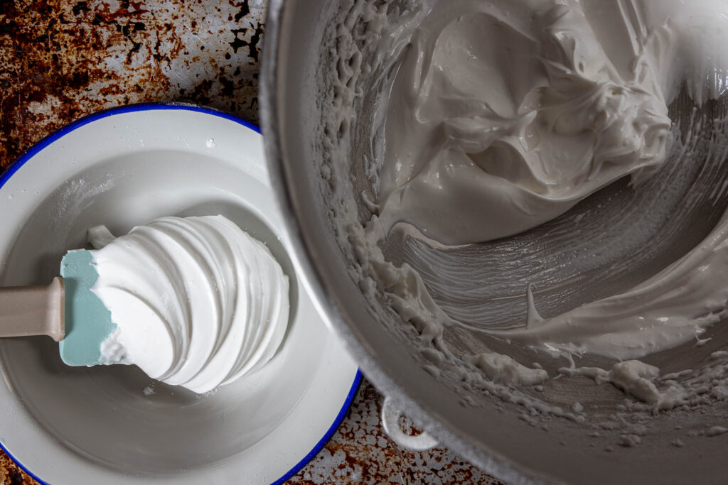 2. Nachdem der vegane Eischnee aus Aquafaba aufgeschlagen ist, wird der Puderzucker eingemixt. Dann nehme ich etwa ein Viertel der Schaummasse für die Glasur ab.