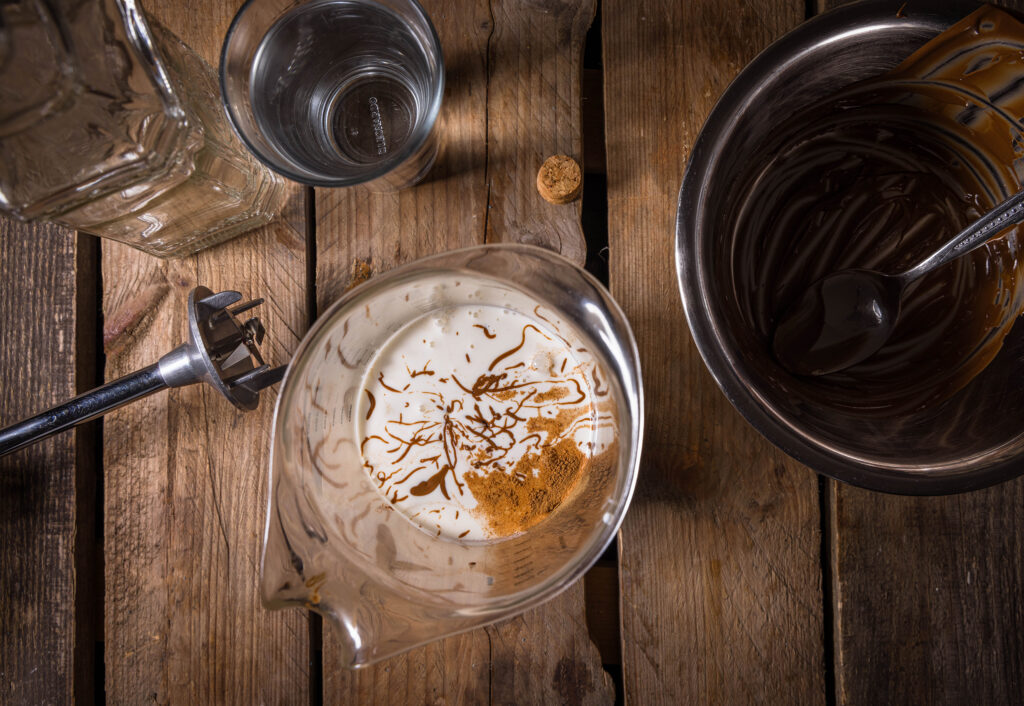 3. Das weiche Nougat, vegane Sahne, Zucker und Zimt in ein hohes Gefäß geben.