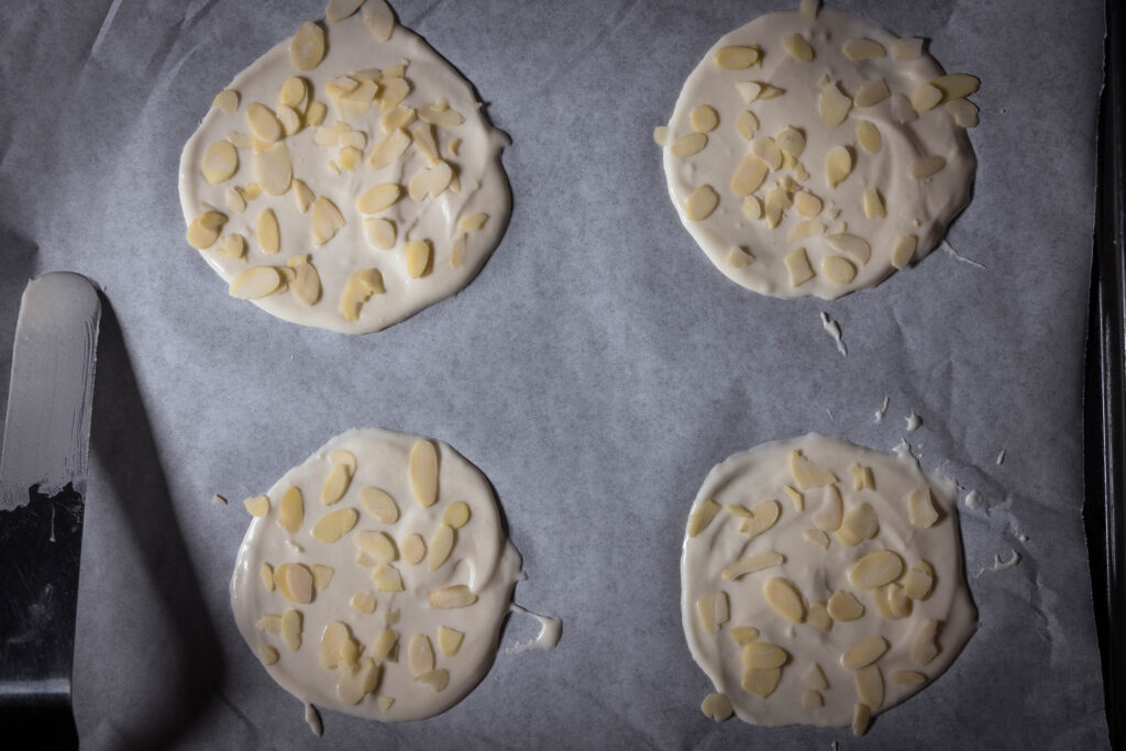 Augestrichener Hippenteig mit Mandelhobeln auf Backblech mit Backpapier