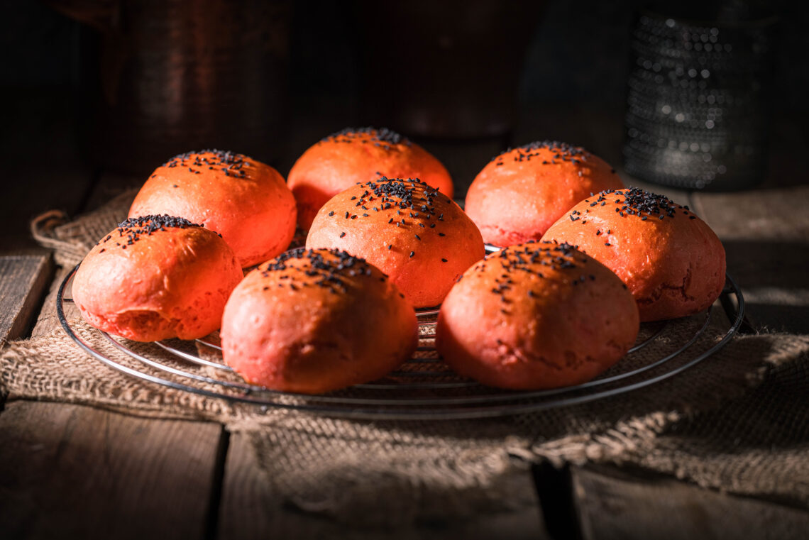 Red Burger Buns auf einem Rost, das auf einem Tuch auf einem Holztisch steht.