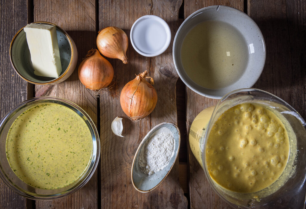 Alle Zutaten für die vegane Käsefonduesuppe auf einem Holztisch.