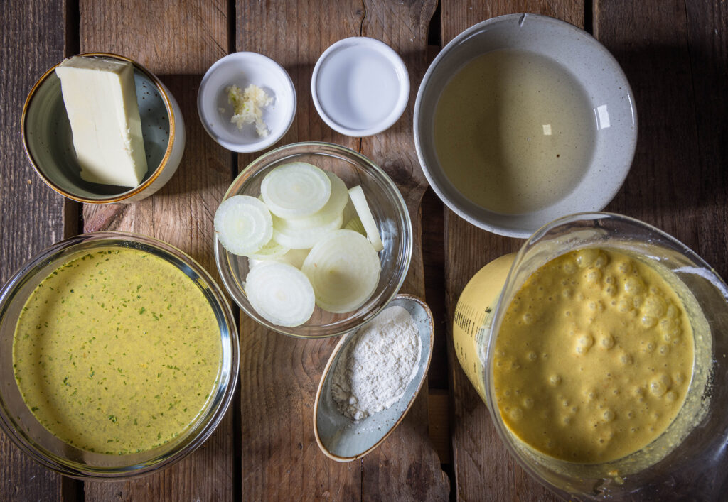 Alle Zutaten für die vegane Käsefonduesuppe auf einem Holztisch.