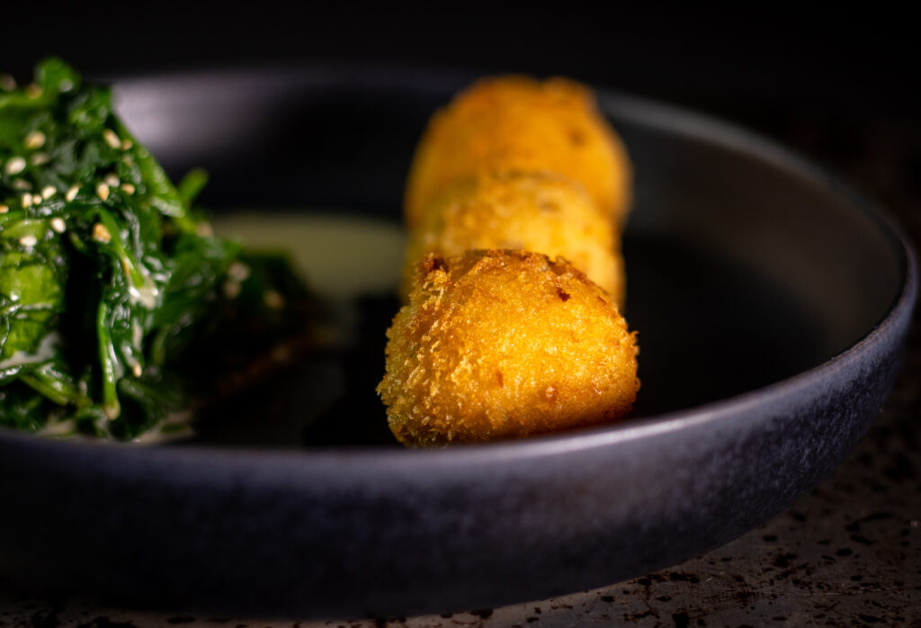 Japanese spinach and  freshly fried vegan mozzarella balls on a plate.