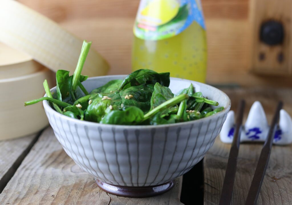 Spinach and sesame salad in a bowl on a wooden table.