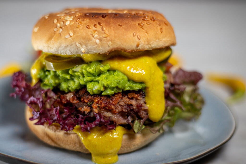 Vegan cheese dip and pea guacamole on an tex mex burger with a kidney bean patty