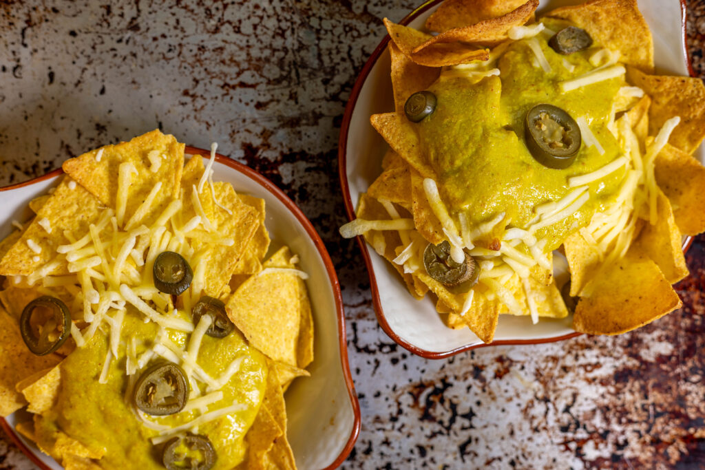 Two bowls with nachos, extra cheese and jalapenos. All vegan.