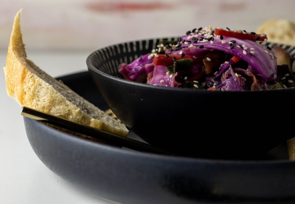 Vegan kimchi in a bowl on a plate with bread.