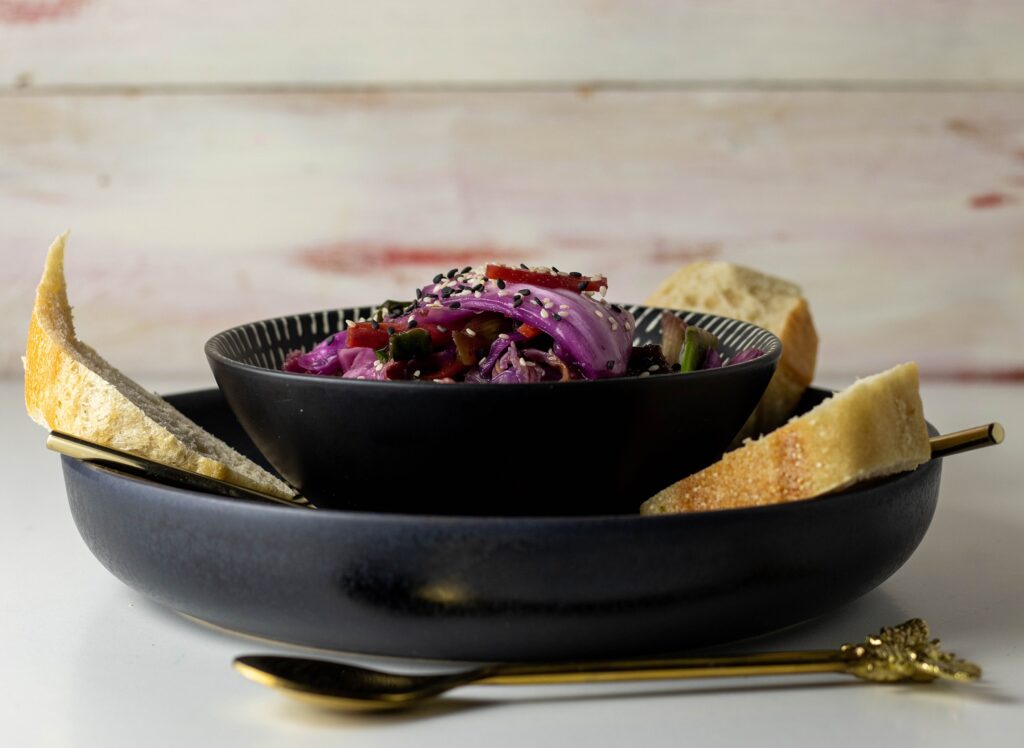 Vegan kimchi in a bowl on a plate with bread.