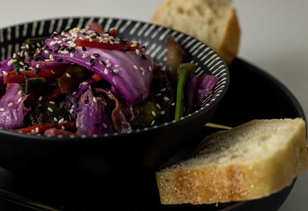 Vegan kimchi in a bowl on a plate with bread.