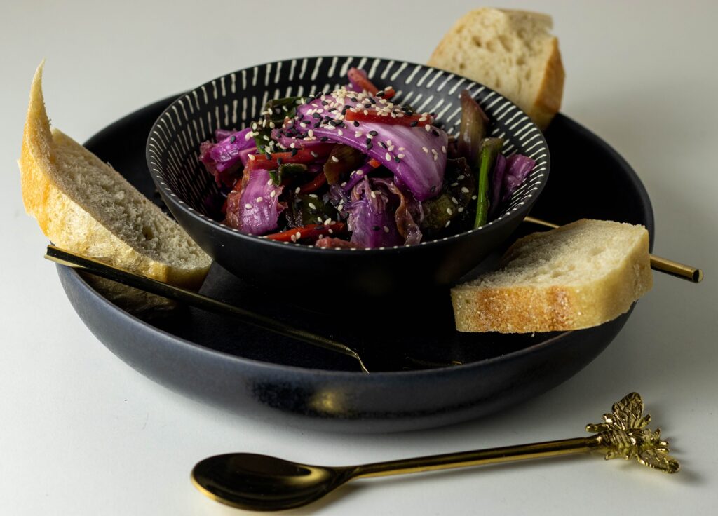 Vegan kimchi in a bowl on a plate with bread.