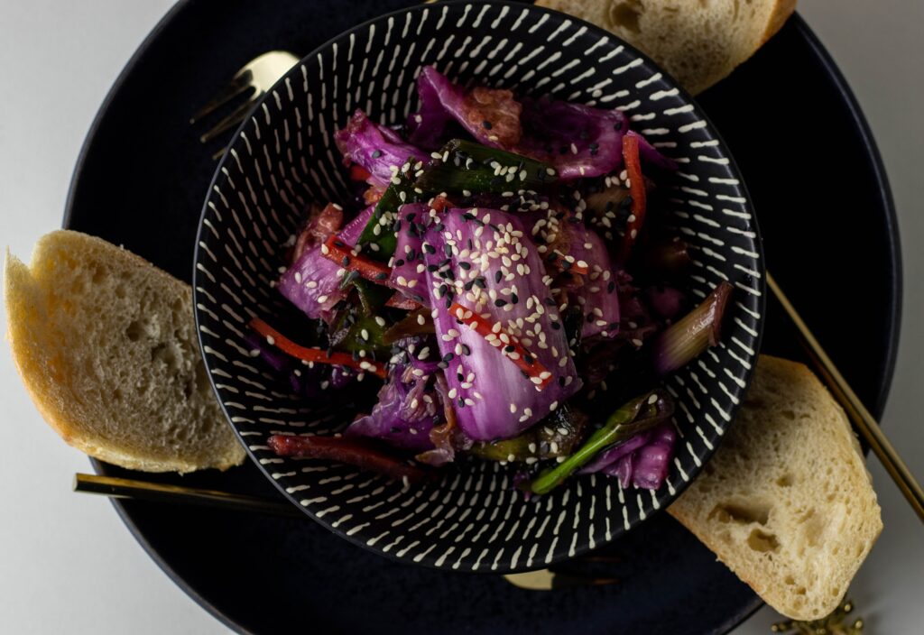 Vegan kimchi in a bowl on a plate with bread.