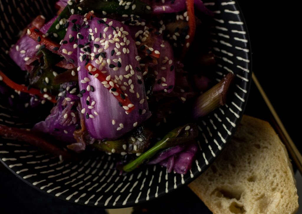 Vegan kimchi in a bowl on a plate with bread.