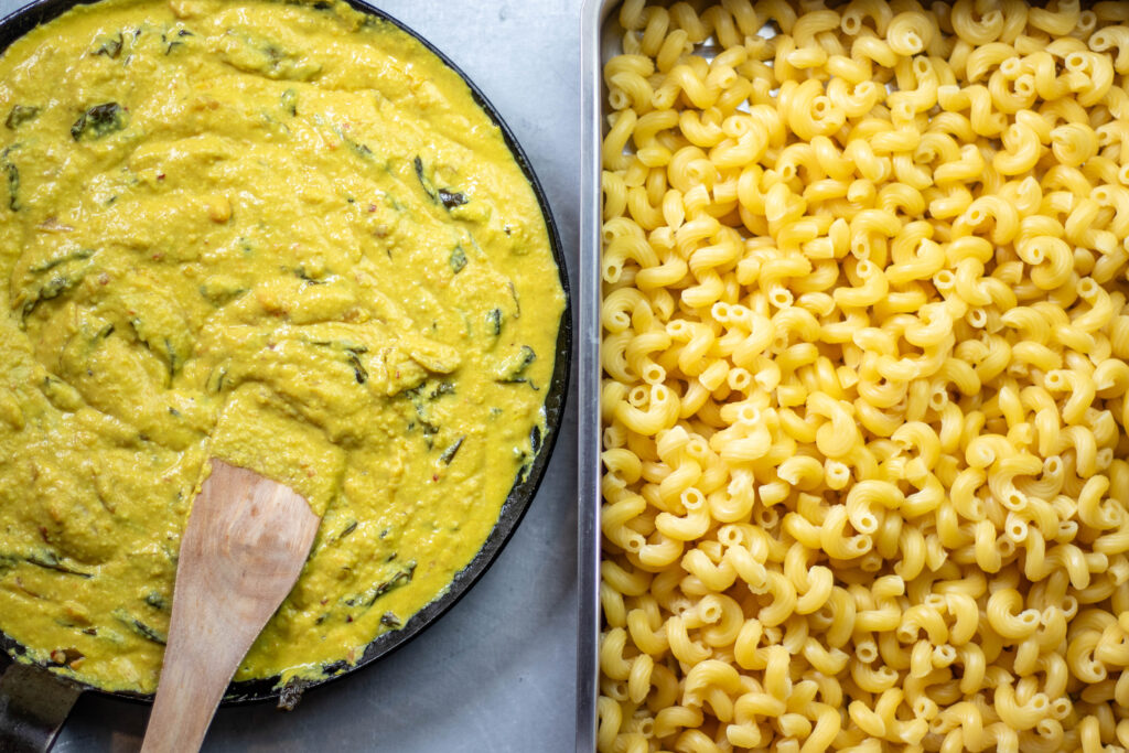 Cheese Sauce in ine pan and cooked pasta in another.