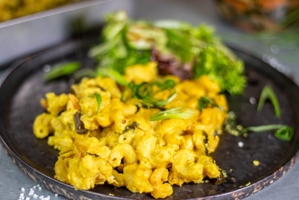 A plate with vegan kimchi mac and cheese as well as a side salad,