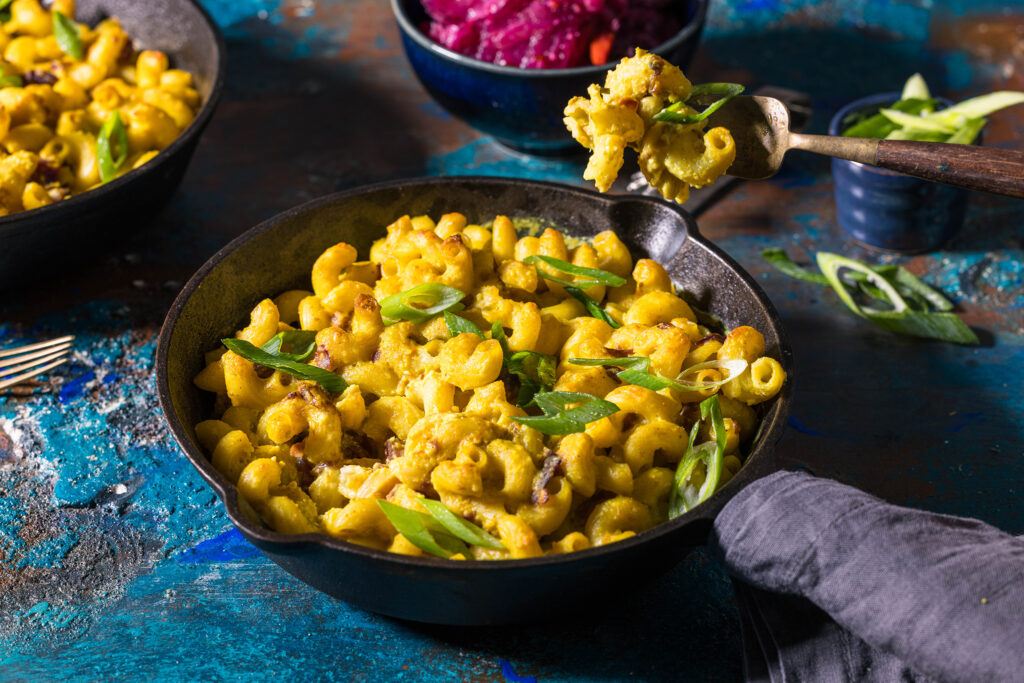 Vegan kimchi mac and cheese in an iron pan. Sprinkled with spring onions.