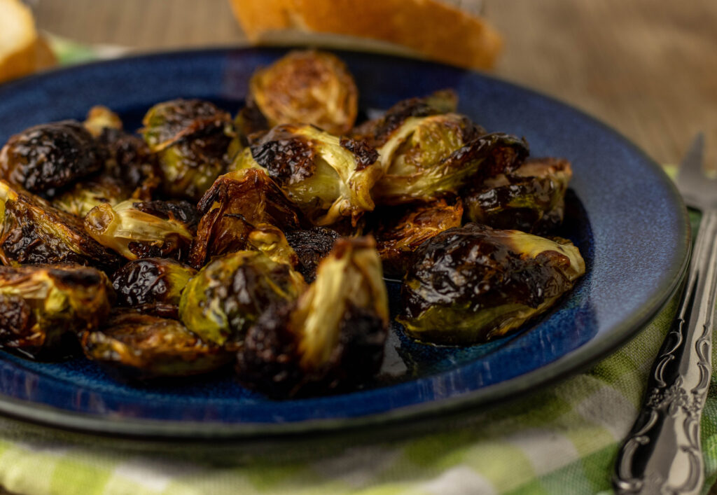 Crispy Brussels Sprouts from the Oven with Balsamic Honey Glaze. On a blue plate.