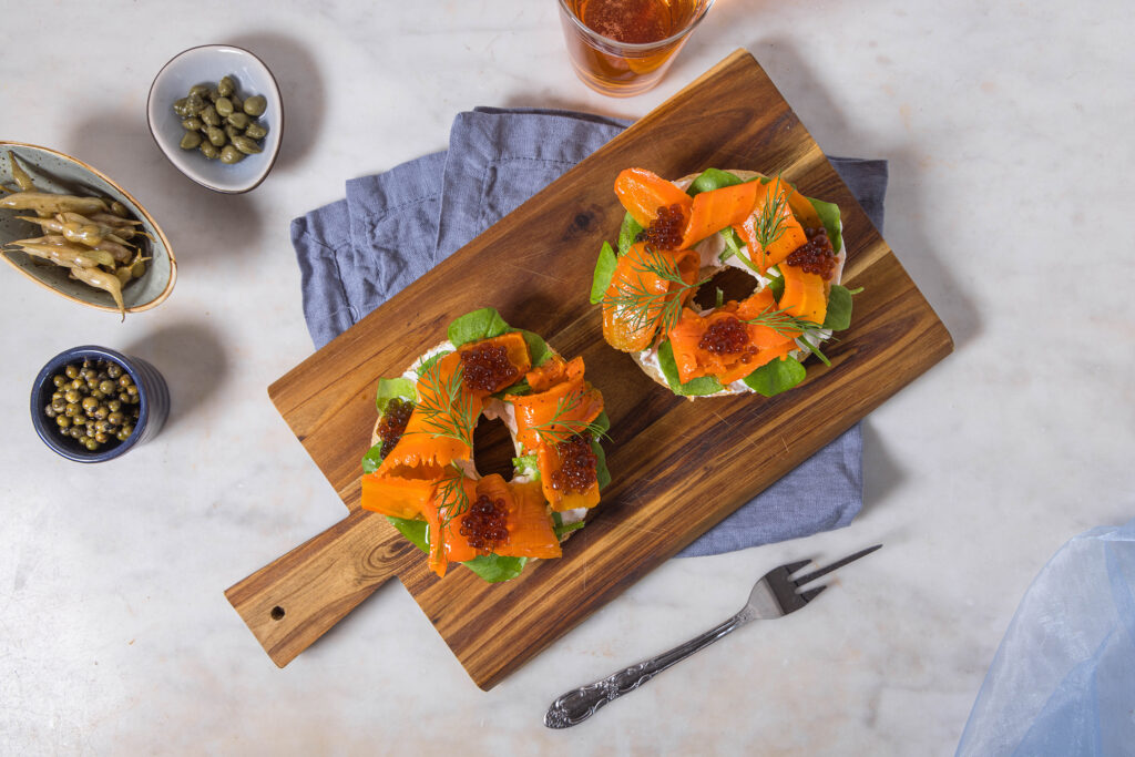 Karottenlachs auf Bagel auf einem Holzbrett auf einem Marmortisch.