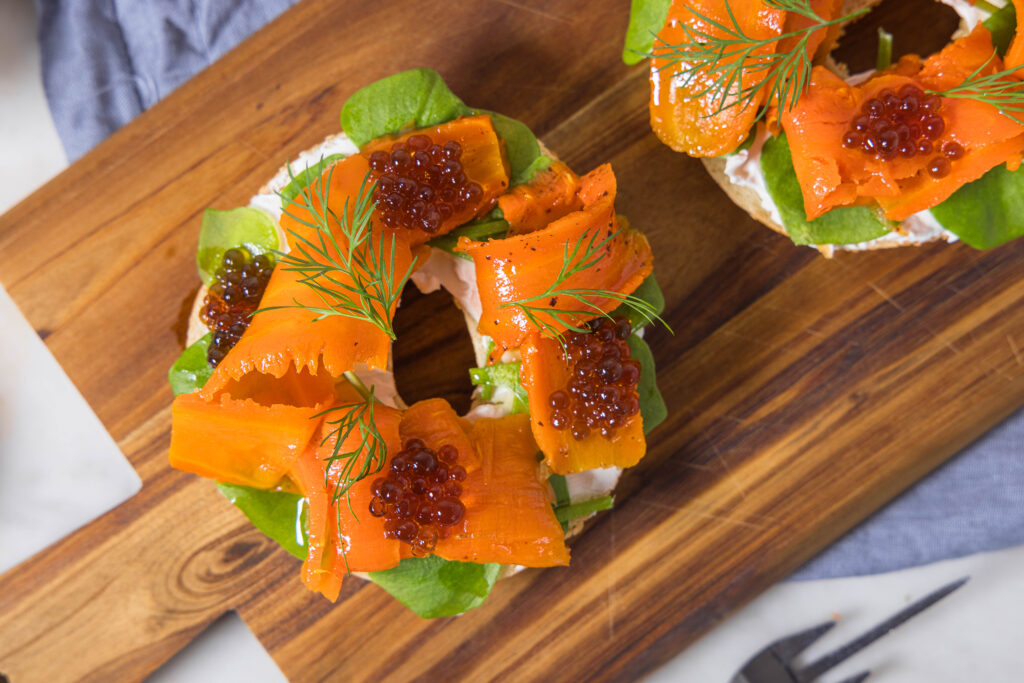 Veganer Lachs aus Karotten mit veganem Kaviar und veganem Firschkäse auf einem Bagel.