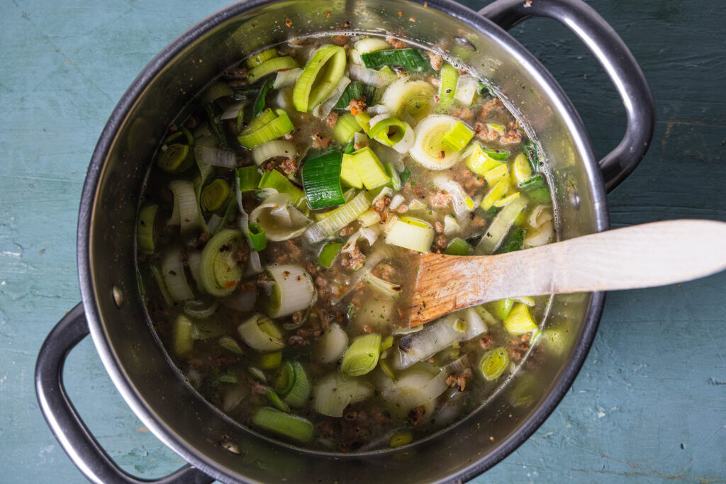 Suppe und Kochlöffel in einem Topf von oben fotografiert.