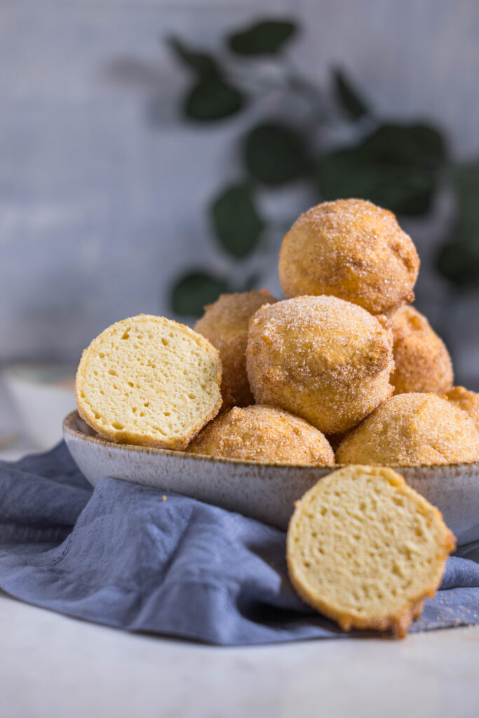 Vegane Quarkbällchen in einer Schale. Eines ist aufgeschnitten. Im HIntergrund ein grüer Zweig.