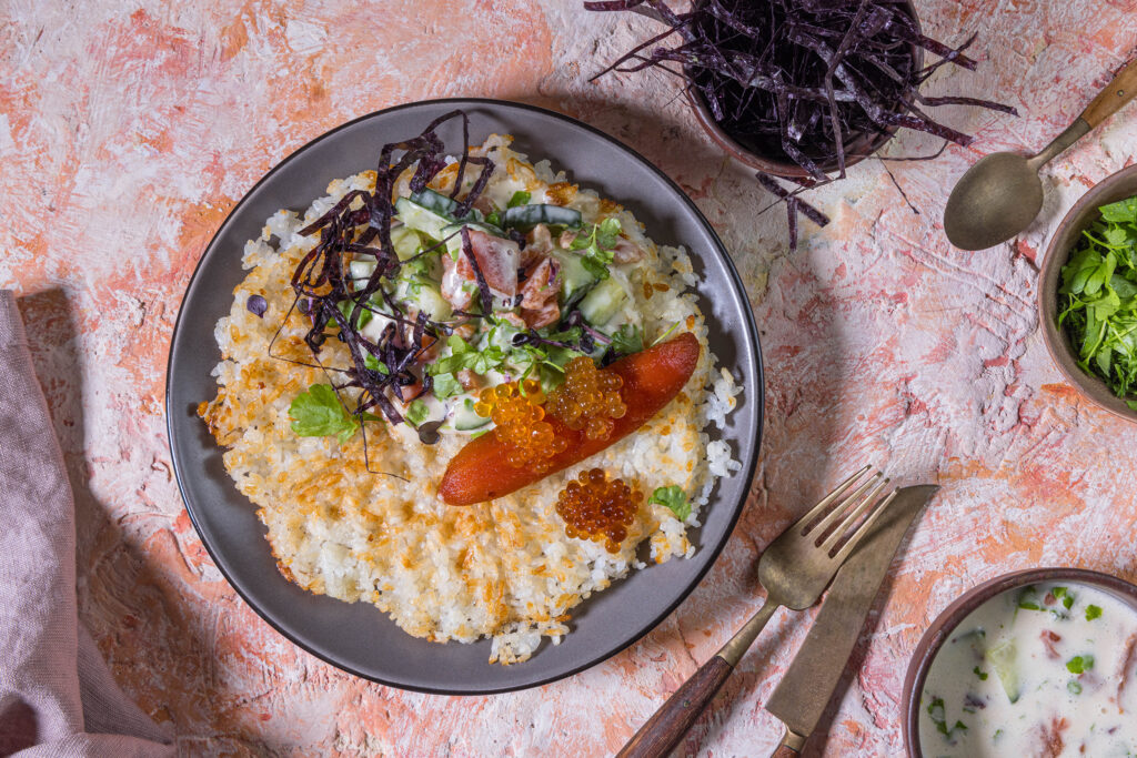 Sushi-Waffel mit veganem Thunfisch-Topping auf einem Teller, daneben Schälchen mit Beilagen