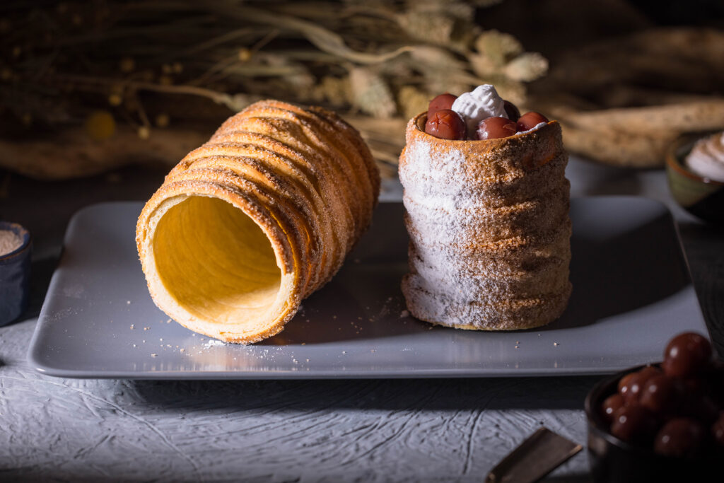 Vegane Baumstriezel - ganz einfach zu Hause gebacken - ein Teil davon gefüllt mit Sahne und Kirschen.