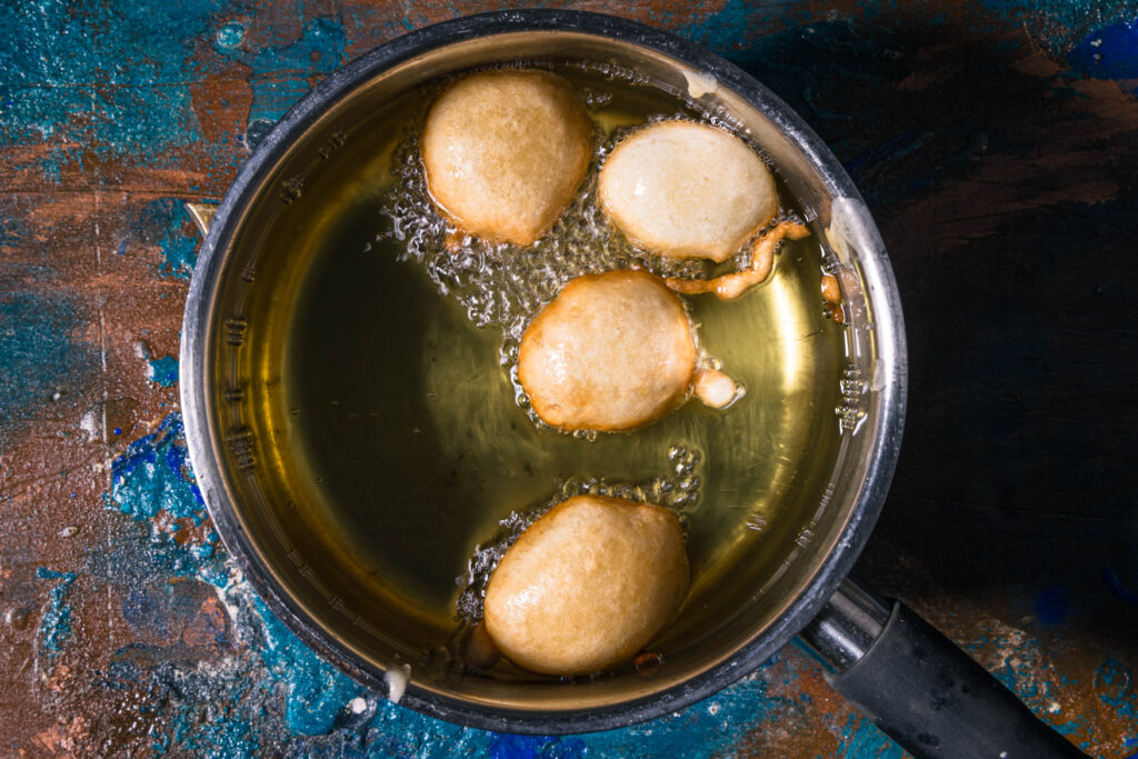 Vier Puff Puffs frittieren in heißem Öl.