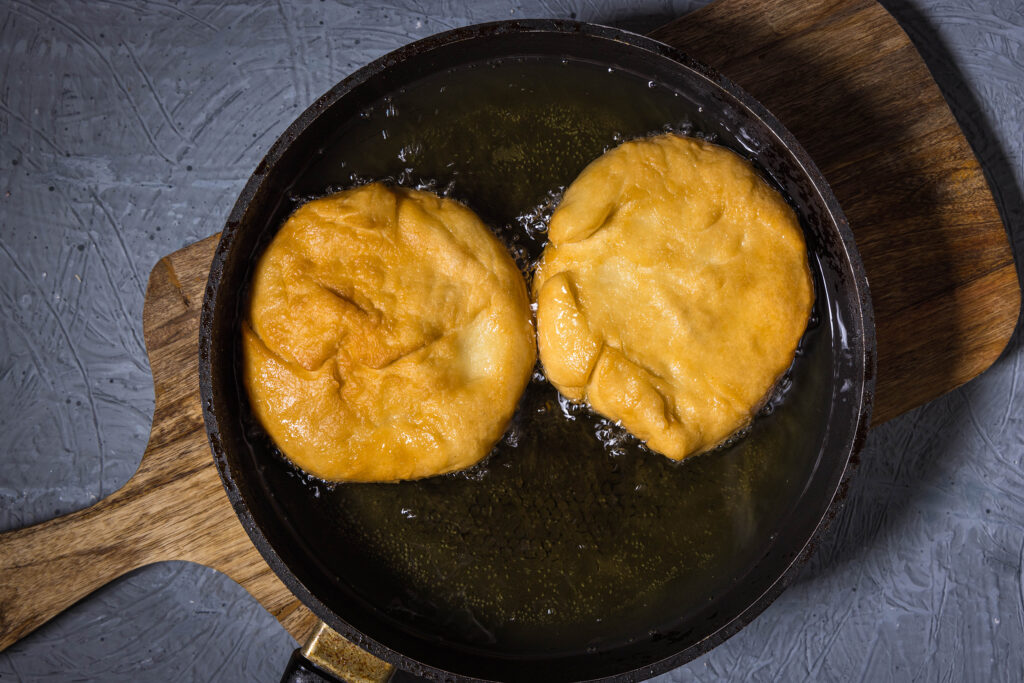 2 Langos in einer Pfanne mit. Sie frittieren tief in Öl.