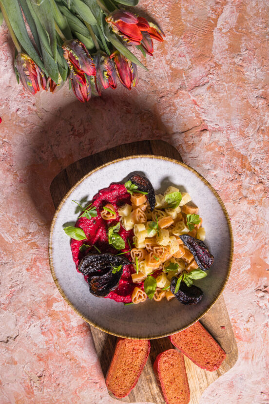 Rote Beete Hummus Sauce für einfache, cremige, aromatische Pasta von oben auf einem Tisch mit Brot und Tulpen.