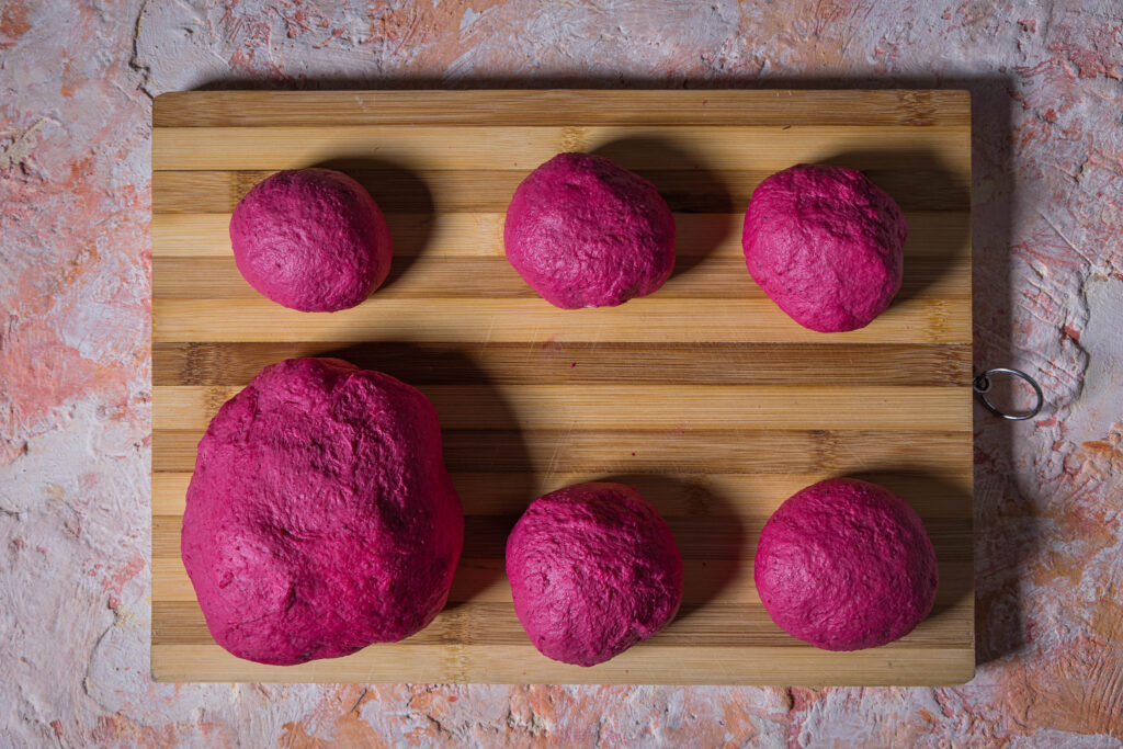 Ein pinker Teigball und mehreren runde Rohlinge für die Pfannenbrötchen.