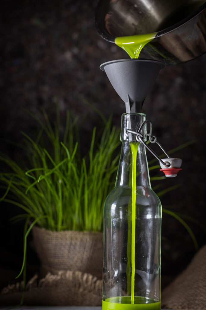 Schnittlauchöl wird in eine Flasche abgefüllt.