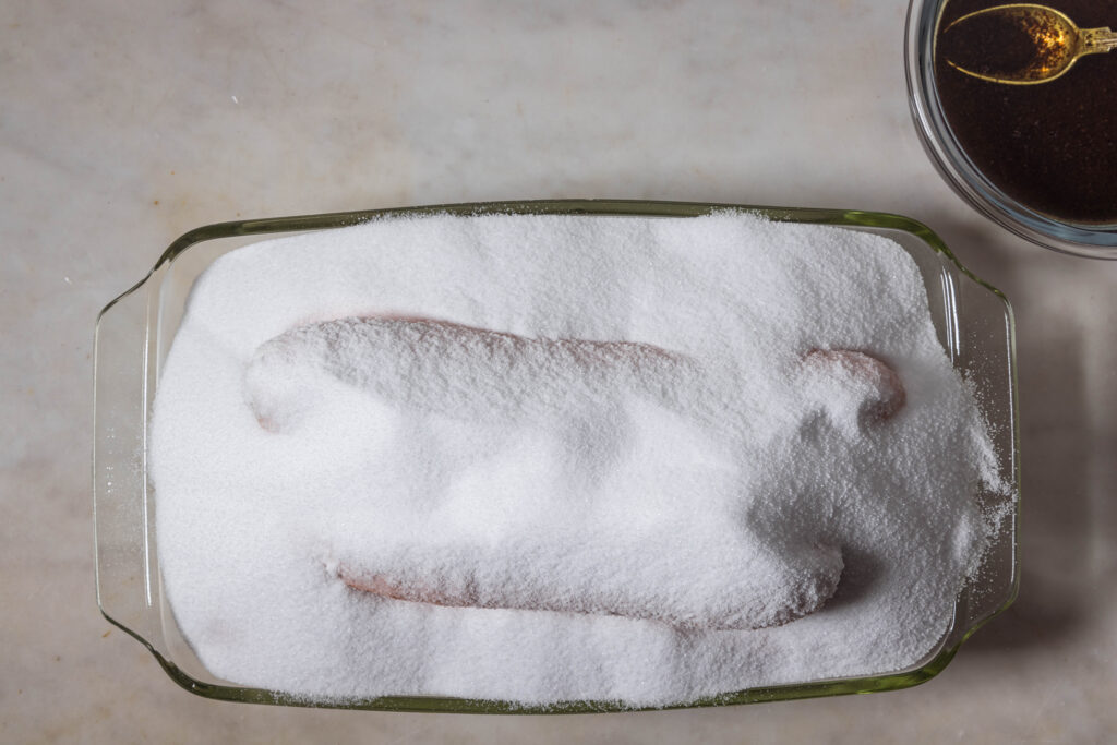 Carrots coated in salt in an oven dish.